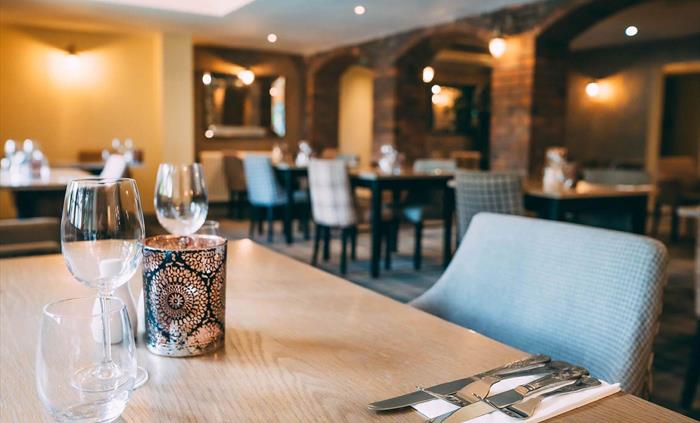 Restaurant at Wild Pheasant Hotel & Spa featuring a tables set with glasses and cutlery, ready for guests, highlighting the elegant dining setup.